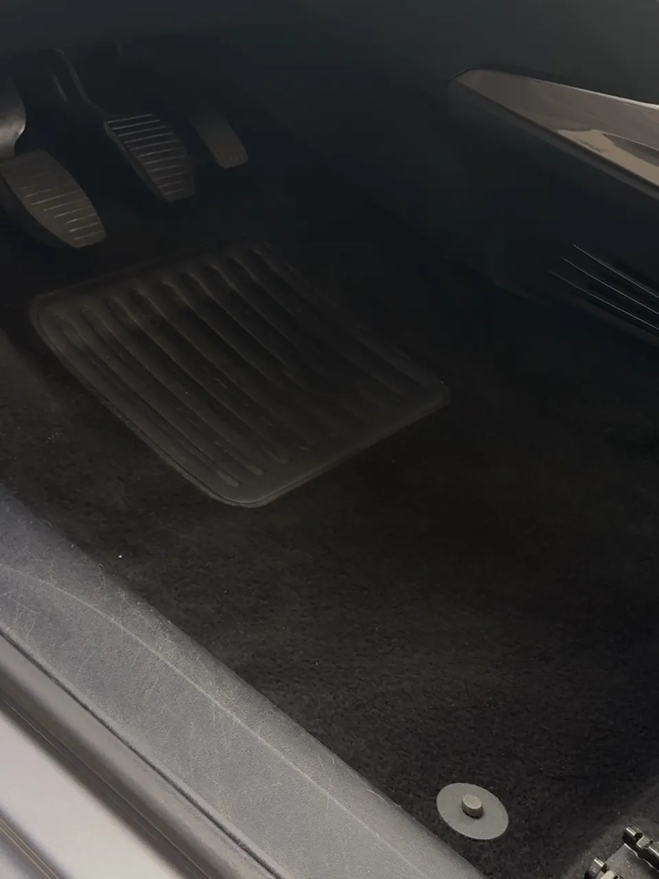 Pédalier et moquette côté conducteur après nettoyage : tapis noir, propre, sans poussière.